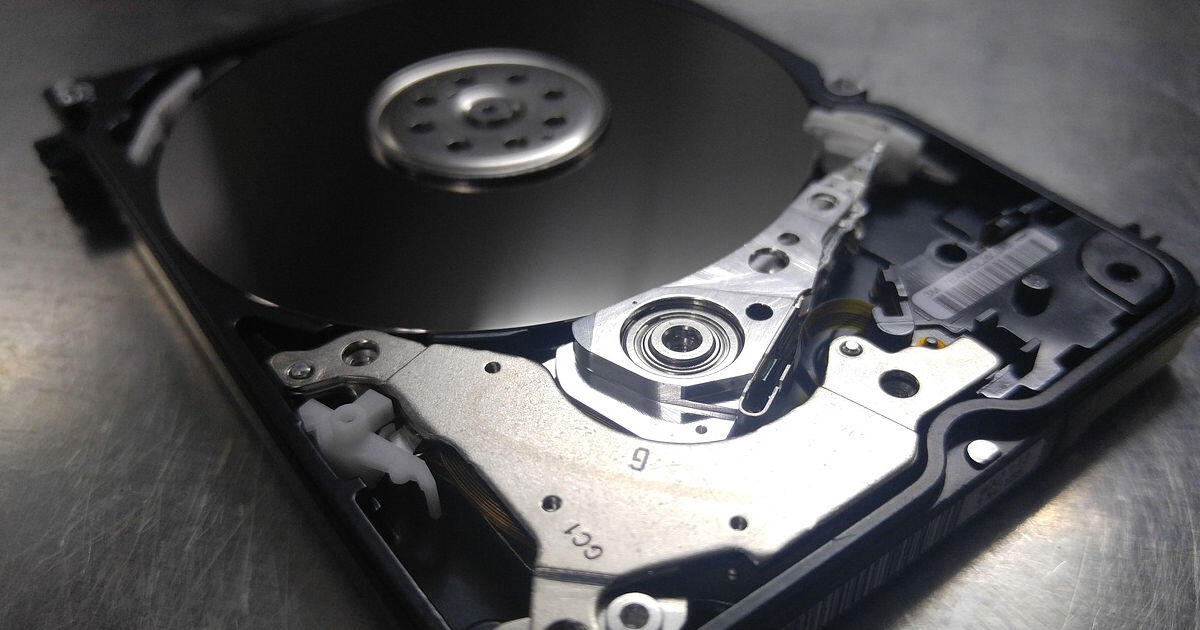 Eine ausgebaute Festplatte als Symbol für Cloud Backup mit geöffnetem Deckel liegt auf einer Metallfläche.