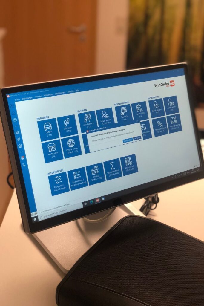 Auf dem Schreibtisch steht eine Touchkasse Modell Colormetrics P5500 und das Programm WinOrder ist geöffnet.